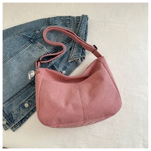 Detail of pink corduroy hobo bag with adjustable strap and decorative charm
