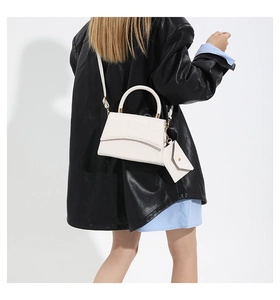 Sac à main blanc à motif crocodile avec pochette porté par un mannequin en veste