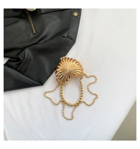 Detailed view of heart-shaped gold metallic shell clutch with elegant bead chain