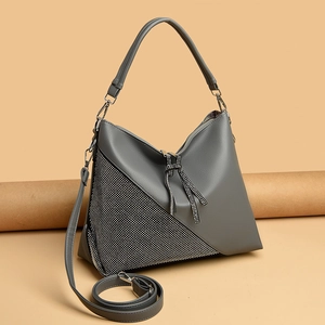 Detail of dark gray crossbody bag featuring a sparkling rhinestone bow and leather texture