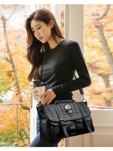 Punk style black leather crossbody bag with silver skull and studs worn by a model