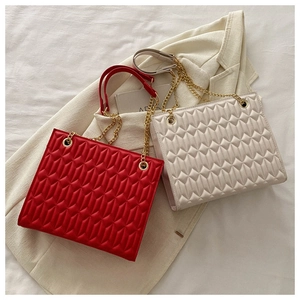Detail of quilted leather texture and golden chain strap on red and cream tote bags