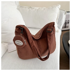 Detail of coffee brown corduroy shoulder bag with small round coin purse on a white sofa