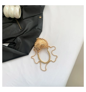 Detailed view of a gold shell-shaped evening bag with pleated metal texture and pearl chain