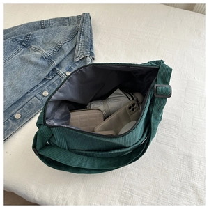 Spacious dark green corduroy tote bag interior with zipper closure and personal items