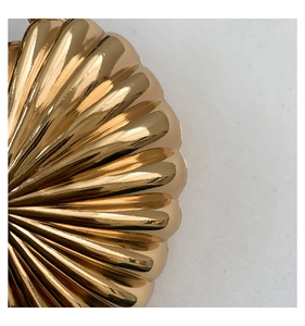 Macro shot of the polished gold ribbed texture and metallic finish on the mini heart bag