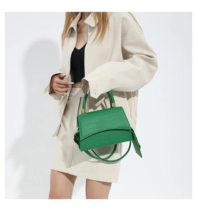 Détail du sac à main vert vif montrant la texture crocodile et la poignée tressée