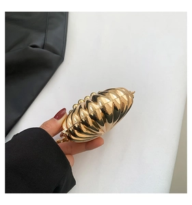 Macro shot of gold pleated metal evening bag with fine chain and heart clasp details