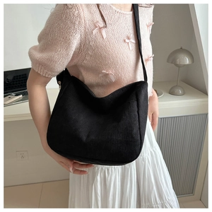 Close-up of black corduroy shoulder bag showing soft ribbed texture and large capacity
