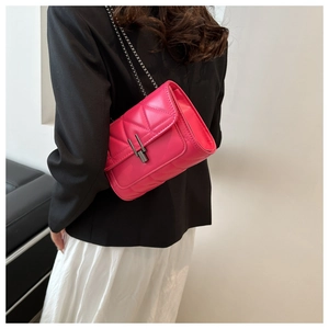Détail d'un sac bandoulière matelassé rose fuchsia avec chaîne porté par un mannequin
