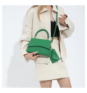 Détail du sac à main vert à motif crocodile avec anse tressée et pochette assortie