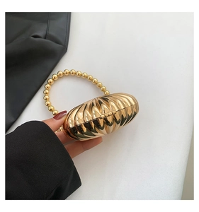 Detail of a golden shell-shaped evening bag with metallic finish and beaded handle