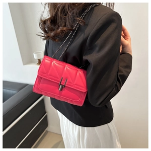 Détail d'un sac bandoulière matelassé fuchsia avec chaîne et fermoir métallique chic
