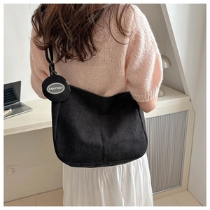 Detail of black corduroy shoulder bag with detachable round coin purse and logo