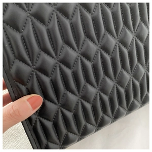 Close-up of high-quality black quilted faux leather handbag with classic geometric pattern