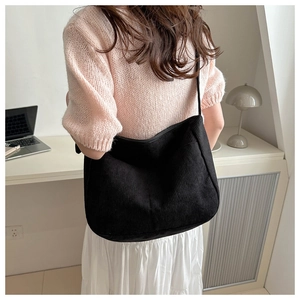Detailed texture of black corduroy shoulder bag shown in a casual lifestyle setting