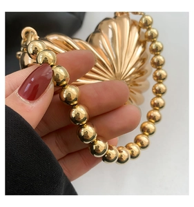Macro shot of heart-shaped gold clutch featuring radial textures and bead chain strap