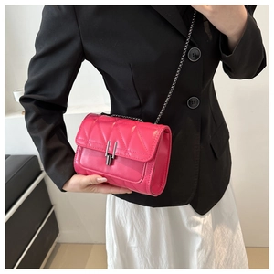 Détail du sac à bandoulière matelassé rose vif avec chaîne sur une veste noire