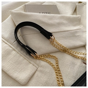 Detail of black leather handle with golden chain link on a trendy crossbody bag