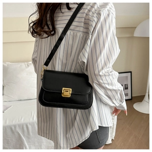 Detail of a vintage black leather crossbody bag with a gold rectangular twist lock clasp