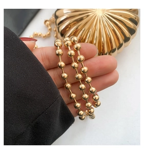 Macro detail of high-gloss gold beaded chain strap and matching shell-shaped evening bag