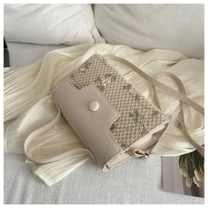 Close-up of floral embroidery on a cream woven shoulder bag with magnetic clasp