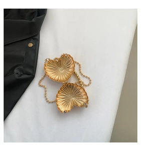 Detail view of a gold heart-shaped metal evening bag with radiant embossed texture and chain