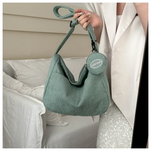 Detail of light green corduroy dumpling bag featuring vertical texture and a mini round pouch