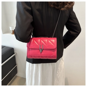 Détail macro du sac matelassé magenta avec motif à chevrons et fermoir en métal gris