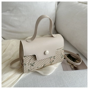 Detail of floral embroidery and woven mesh texture on the cream white handbag