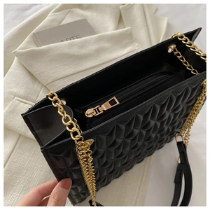 Detail view of black quilted chain bag showing spacious interior and golden zipper pocket