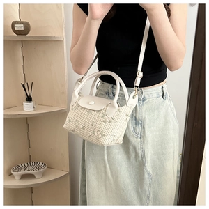 Détail du sac à main tissé beige avec broderie florale et bandoulière en cuir blanc