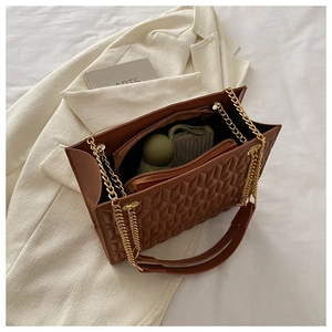 Detail of deep brown quilted tote interior showing spacious main compartment and chain strap