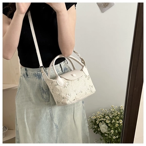 Détail du sac à main tissé crème avec broderie florale verte et poignée supérieure