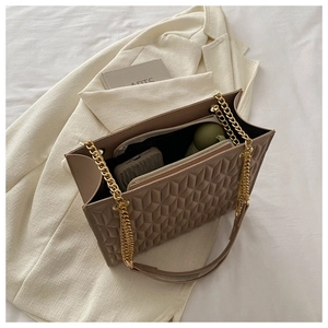 Detail of tan quilted tote bag with gold chain strap, showing spacious interior compartment