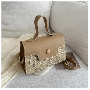 Detail of woven handbag featuring leather flap and delicate floral embroidery pattern