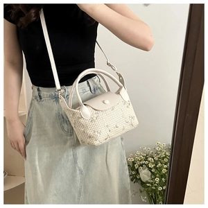 Détail d'un sac tressé avec broderie florale et poignée en cuir blanc sur une femme