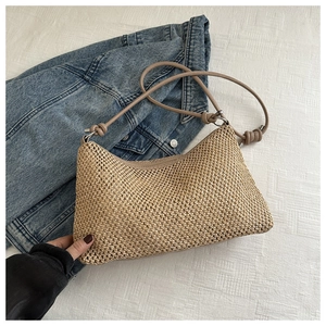 Detailed close-up of woven straw tote bag with knot strap and silver metal rings