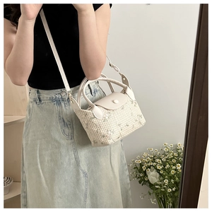Détail du sac en paille tressée avec broderie florale et finitions en cuir PU