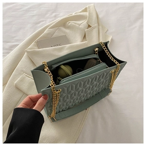 Internal storage detail of mint green quilted tote with golden chain and zipper pocket