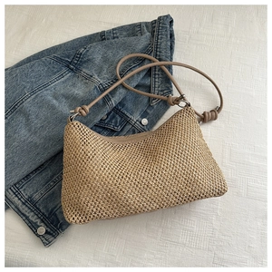 Detail of woven straw tote bag with intricate mesh pattern and knotted leather straps
