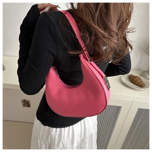 Pink crescent moon shoulder bag with silver hardware on a person in a minimalist setting