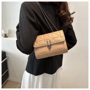 Gros plan du sac à bandoulière matelassé beige avec chaîne porté par un mannequin