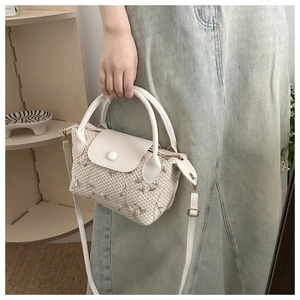 Détail d'un sac à main en tricot blanc avec broderie florale et bandoulière en cuir