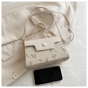 Detail of beige tote bag with delicate green floral embroidery on suit background