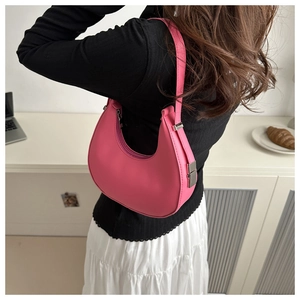 Detail of pink crescent bag with smooth leather finish and silver buckle on model