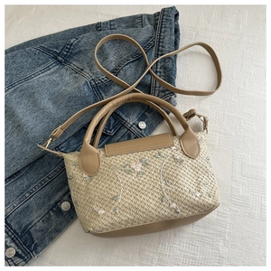 Détail du sac à main tissé beige avec broderie florale rose et bandoulière en cuir