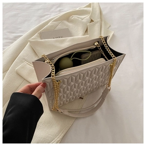 Detail of spacious beige quilted tote bag interior with gold chain and leather straps