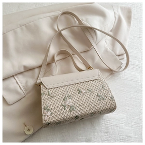 Close-up of cream woven handbag featuring pink and green floral embroidery detail