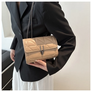 Petit sac à bandoulière matelassé beige avec chaîne en métal porté par un mannequin